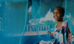 Girl with antimalarial-treated bed net. Courtesy of Against Malaria Foundation.